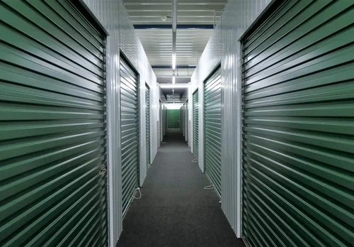 A long hallway with green self storage units.
