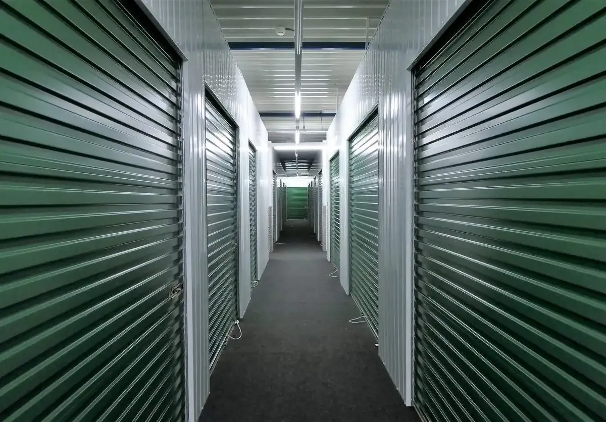 A long hallway with green self storage units.