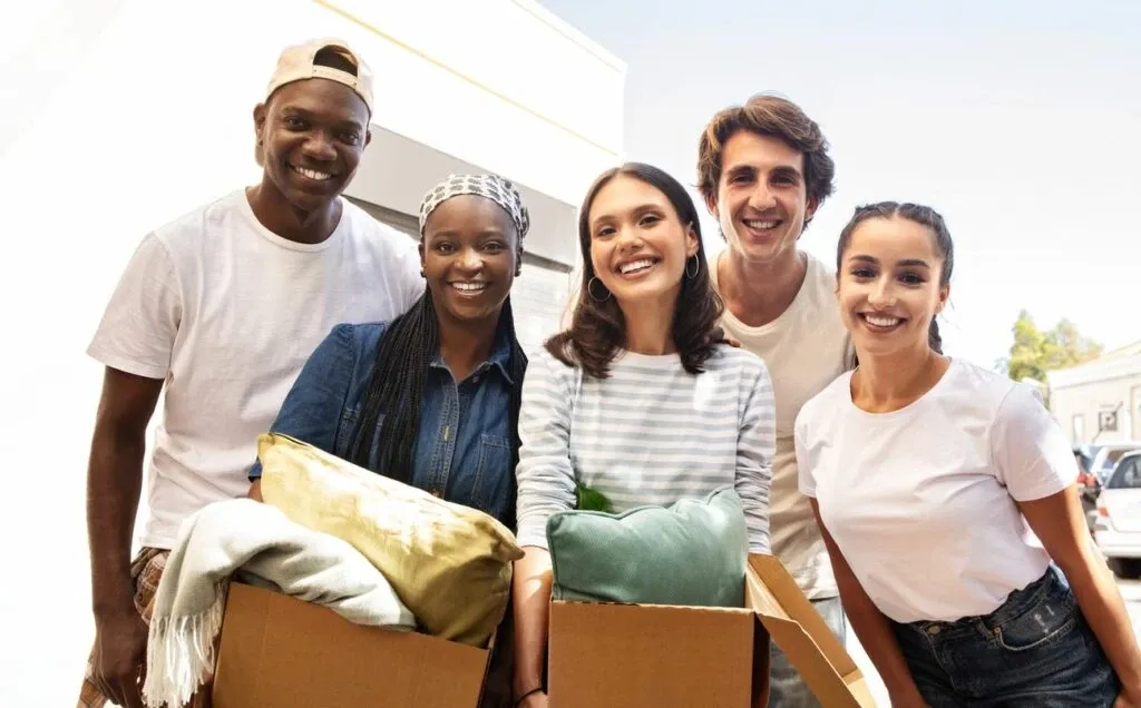 A group of students smiling for a portrait to commemorate moving into their college dorm.