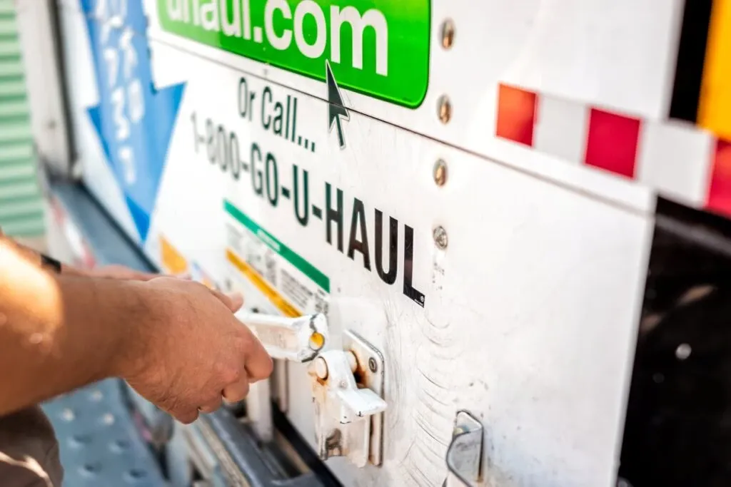 A man shuts the door of a moving truck while moving into a storage facility. 