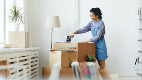 Woman taping a storage box closed.