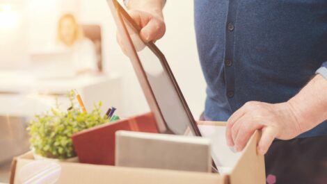 A man packs a picture frame into a box of miscellaneous items