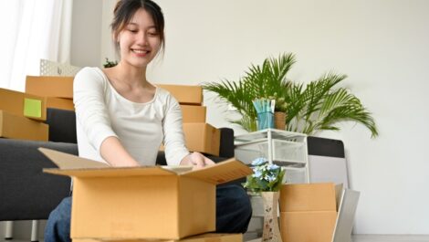 A woman unpacks her belongings out of boxes as she moves into a new apartment.