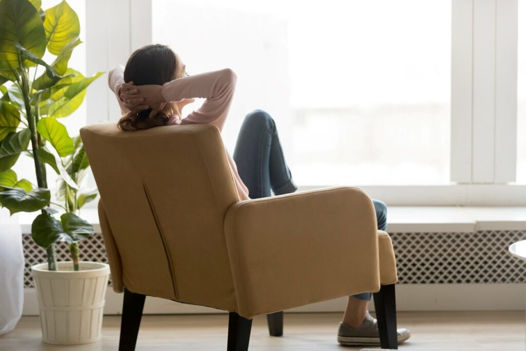 Young woman sitting in a chair looking out a window and enjoying a calm environment.