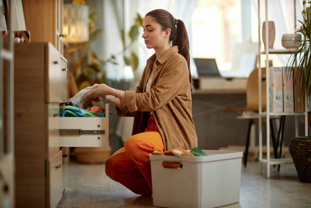 A woman storing clothing in a drawer.