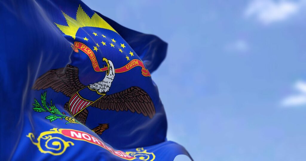 North Dakota state flag waving in the air with blue sky in the background.