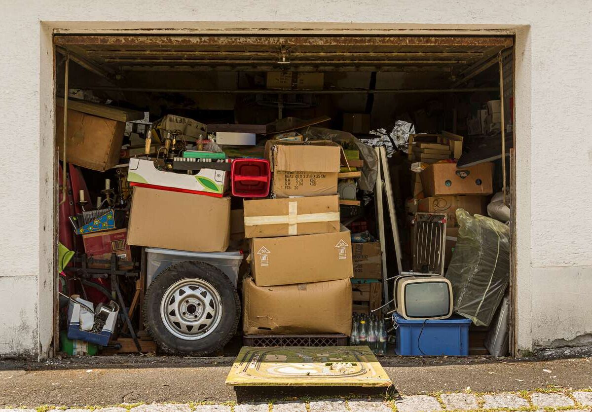 A garage with its door open and jam-packed with clutter.