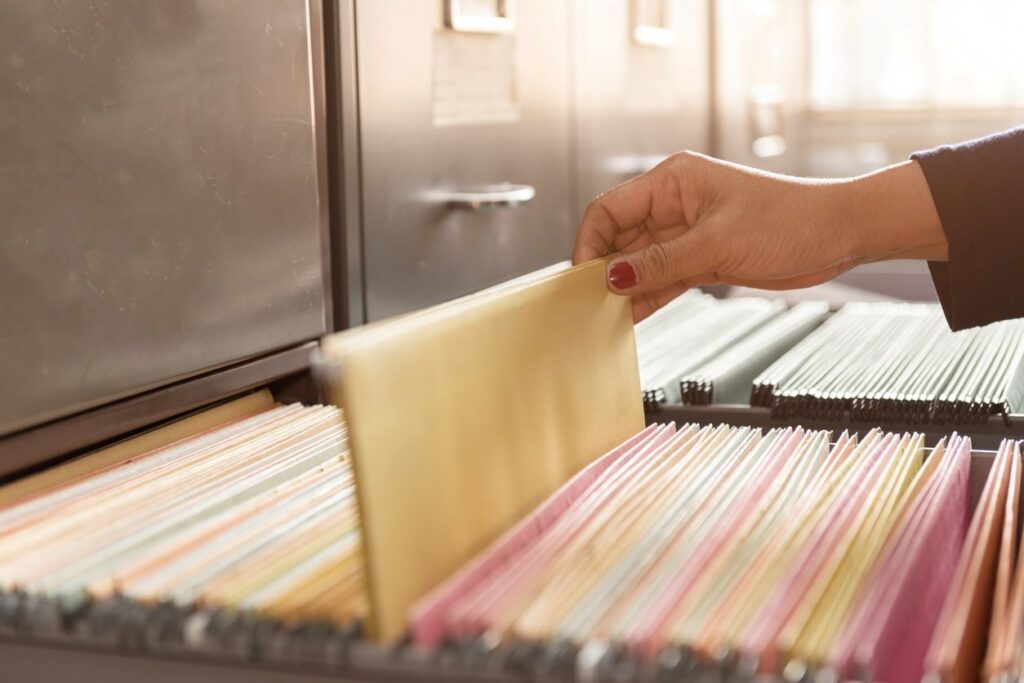 A woman grabbing a folder from a filing cabinet.